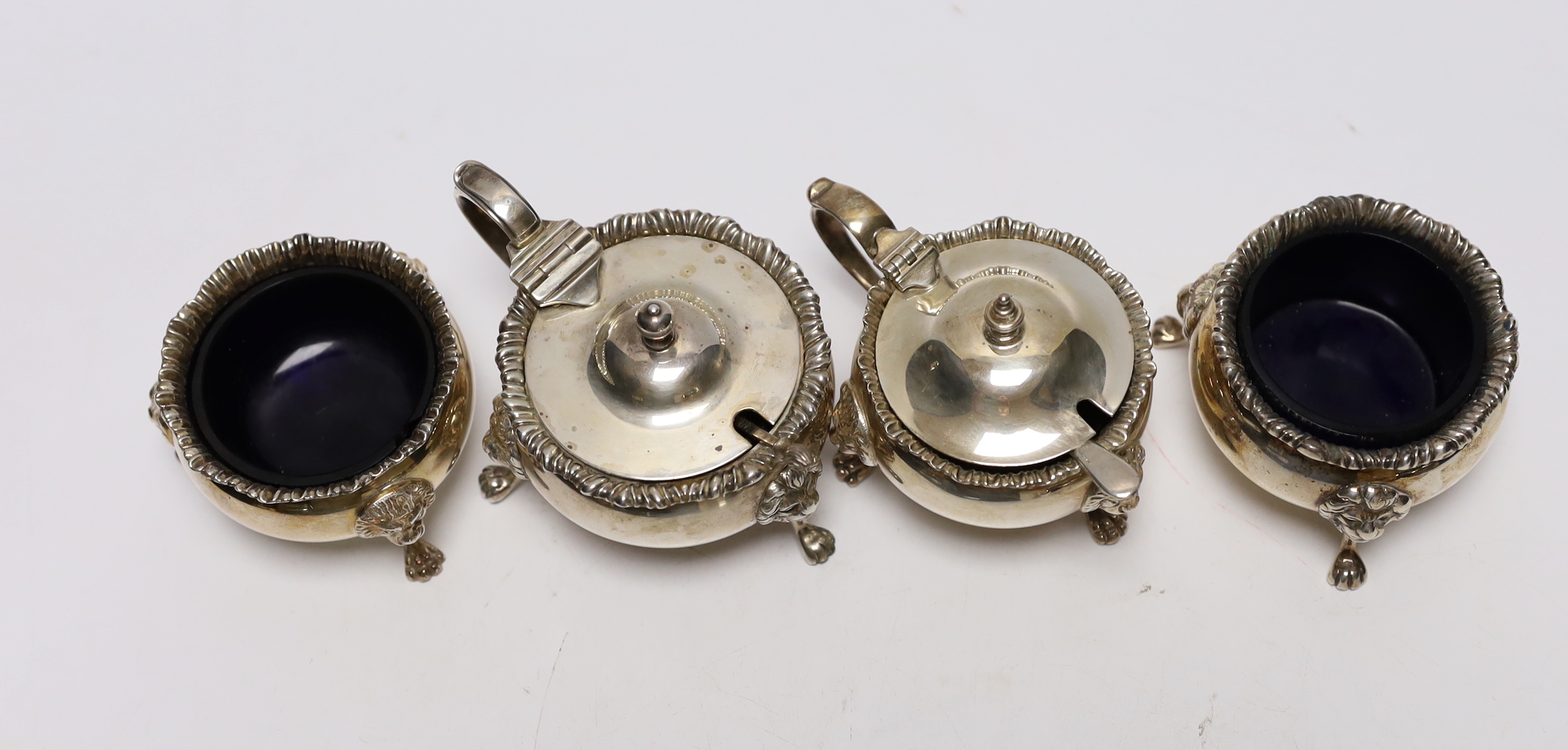 An Elizabeth II silver four piece condiment set by Garrard & Co, London, 1971/73, with blue glass liners and two associated spoons.